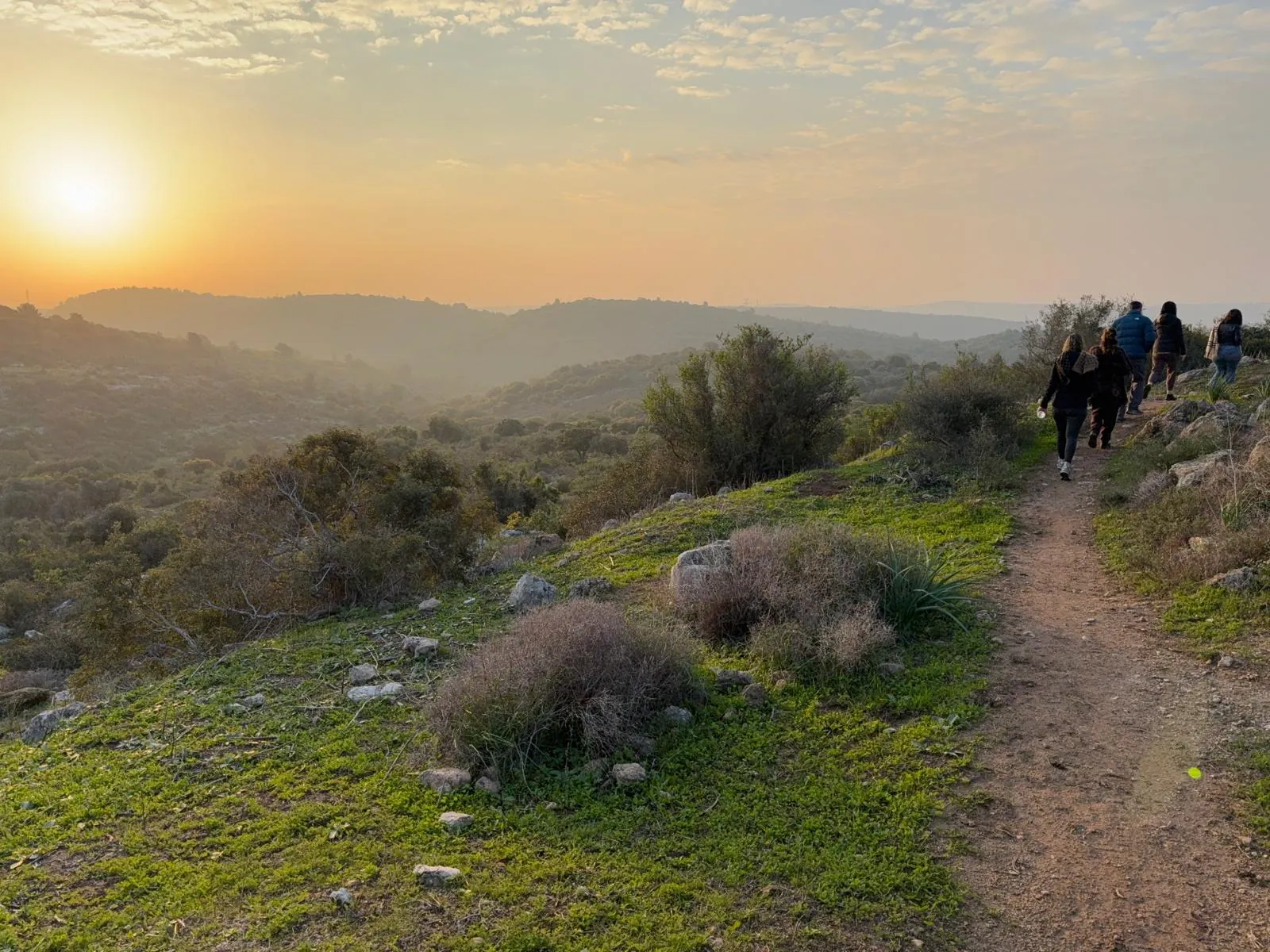 קבוצת המשתתפים הולכת בשביל בגבעות בזריחה של בוקר דצמבר