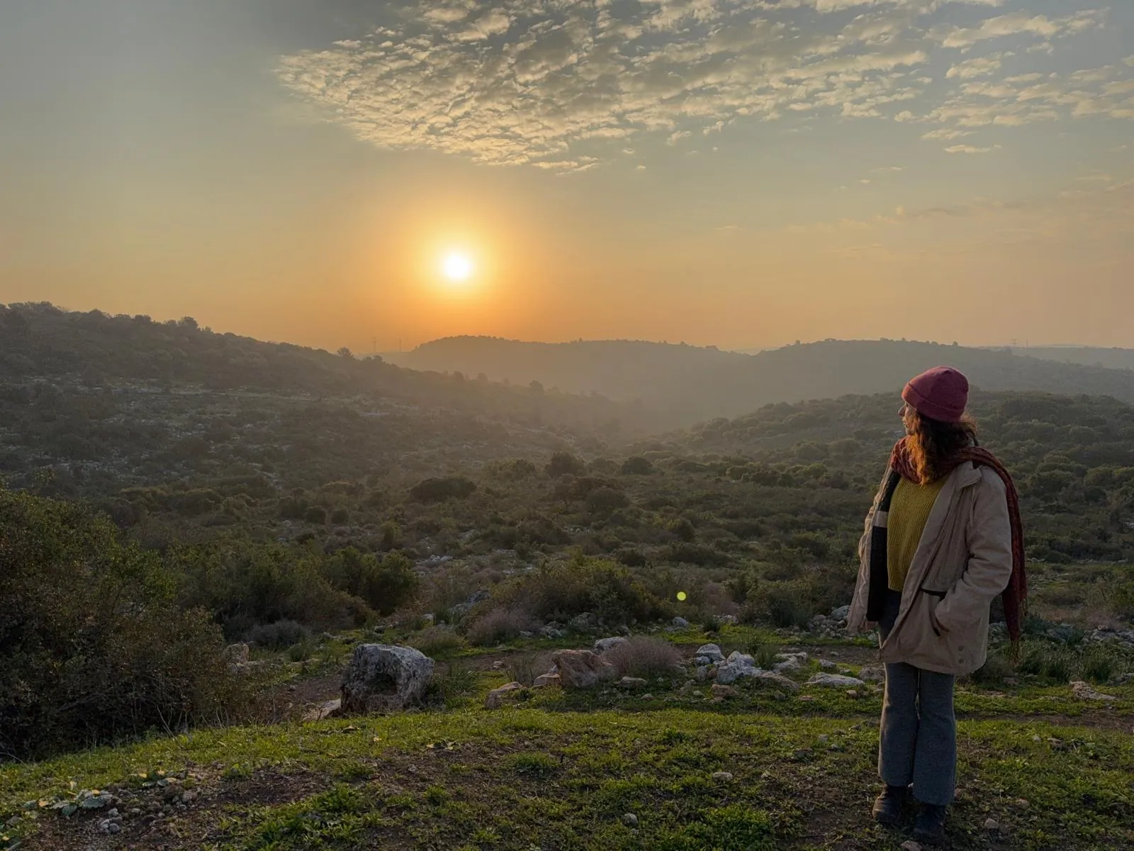 משתתפת עומדת על גבעה ומביטה בשמש העולה